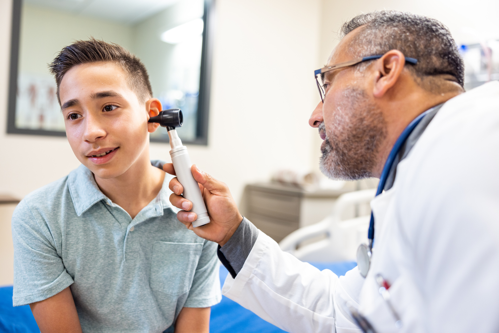Doctor examining a boy's ear with an otoscope