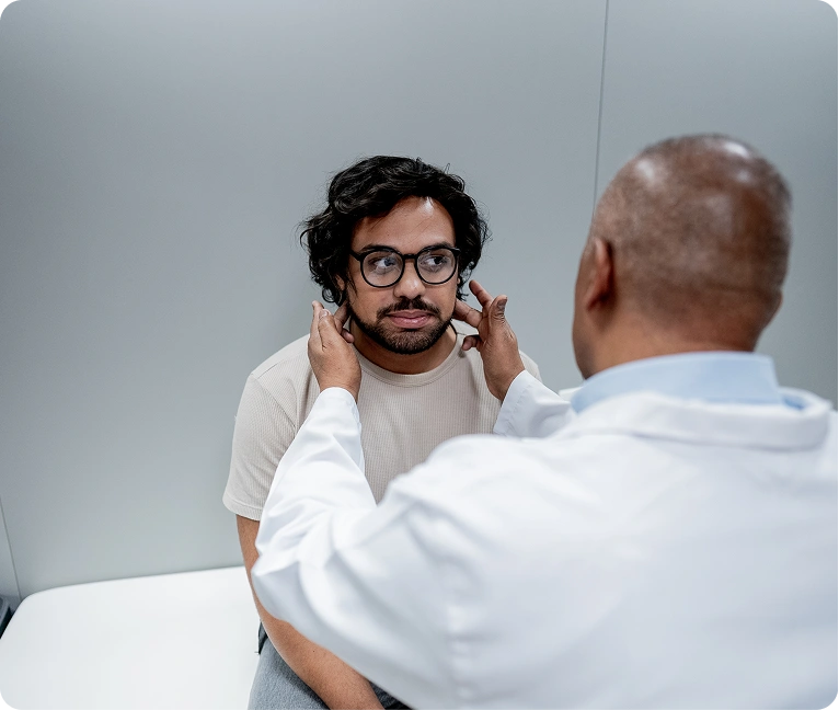 Man wearing glasses getting his ear examined by a doctor