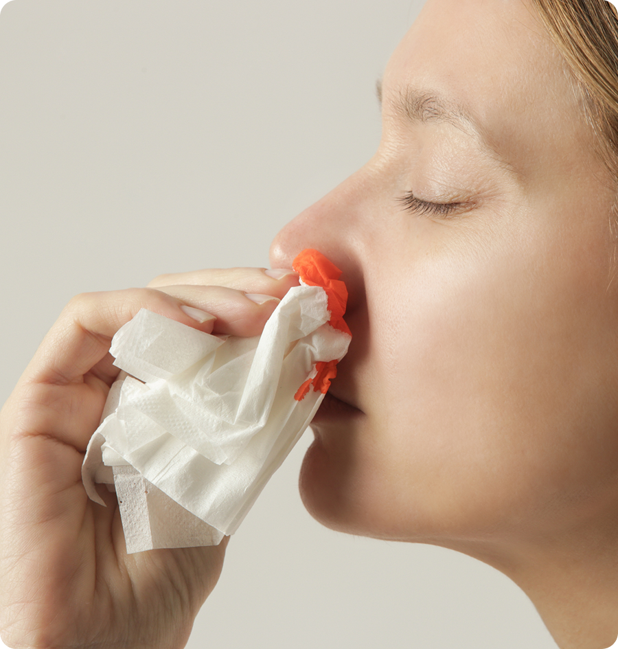 Woman blowing her nose with a tissue in her hand against a white background