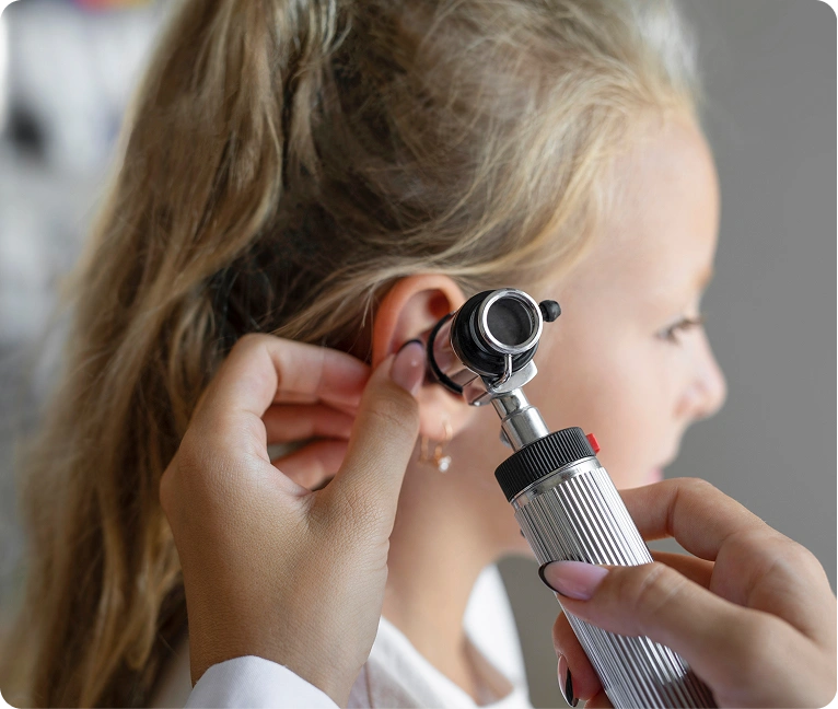 Little girl getting her ear examined by a doctor, holding an otoscope in her hand