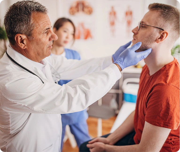 Doctor wearing a stethoscope and gloves examining a patient's throat
