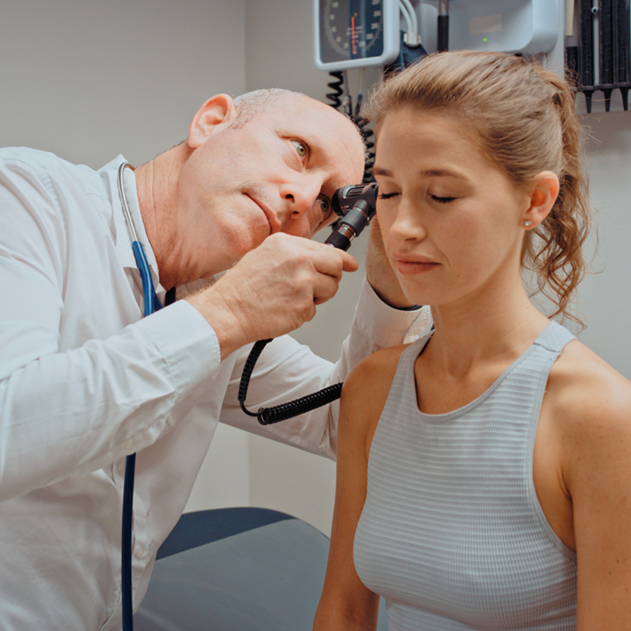 Doctor examining a patient's ear with a stethoscope while holding a microphone