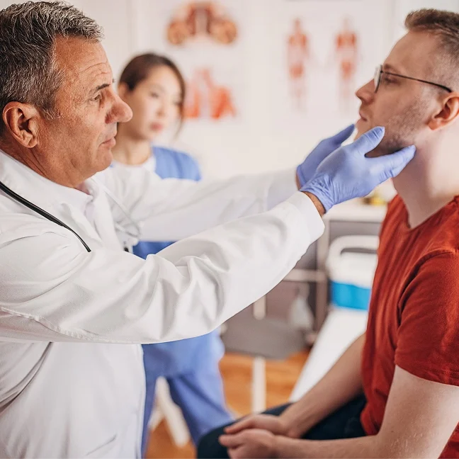Doctor wearing a stethoscope and gloves examining a patient's throat